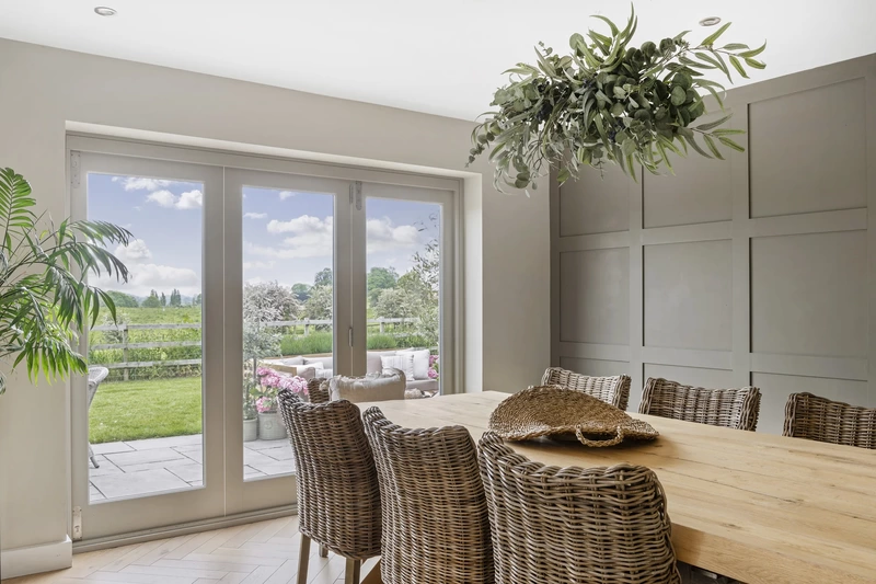Dining room with wicker chairs and view through bi-folding doors