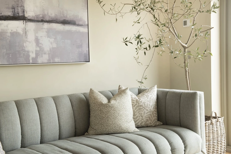 Detail photo of sofa with painting behind and plant to one side