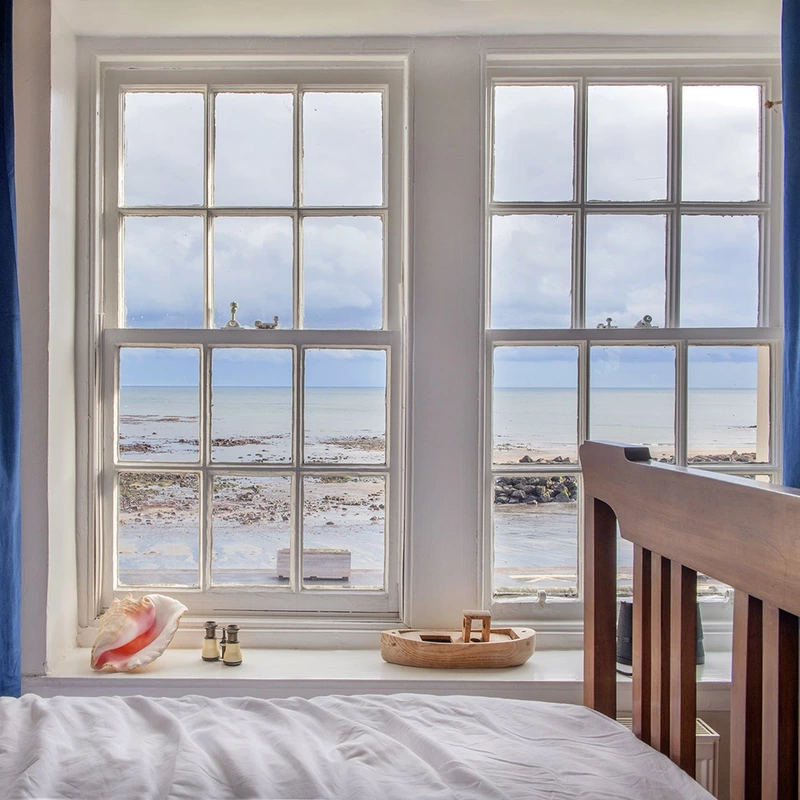 Bed next to big window with sea view