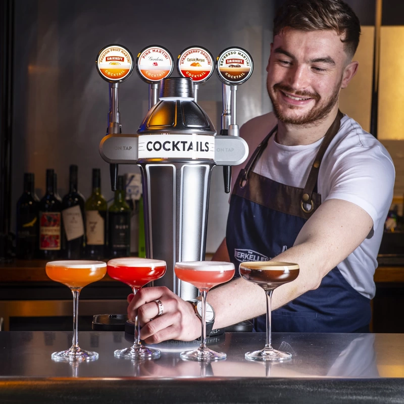 A barman pouring 4 draught cocktails at the bar