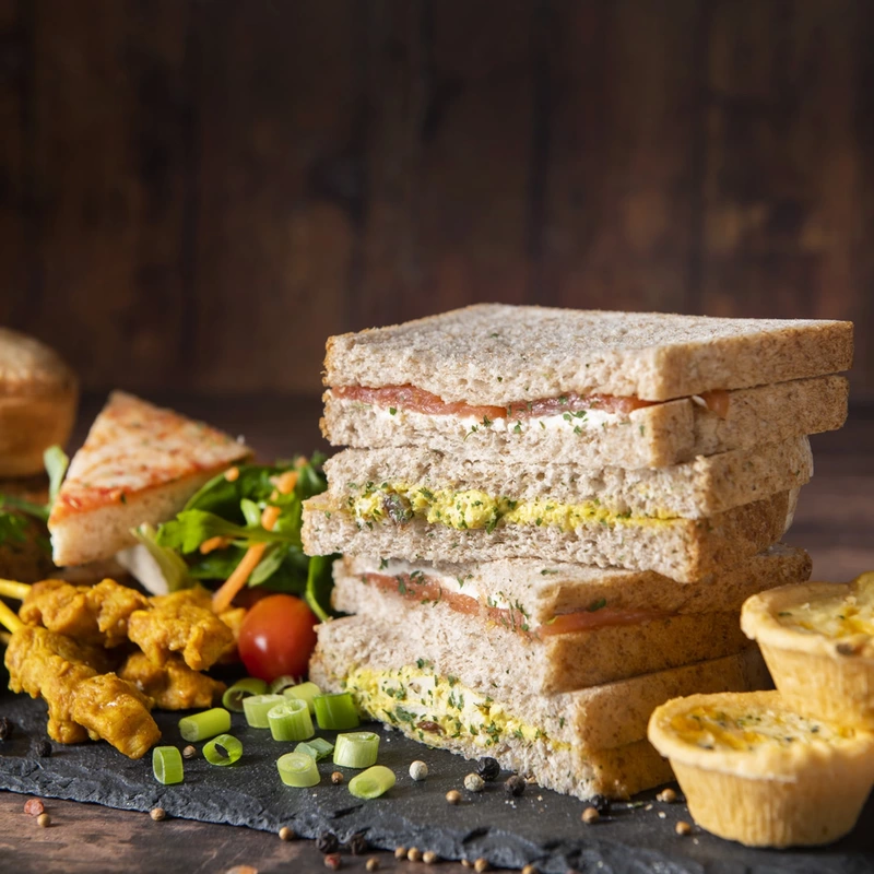 Freshly made sandwiches on a slate with buffet snacks
