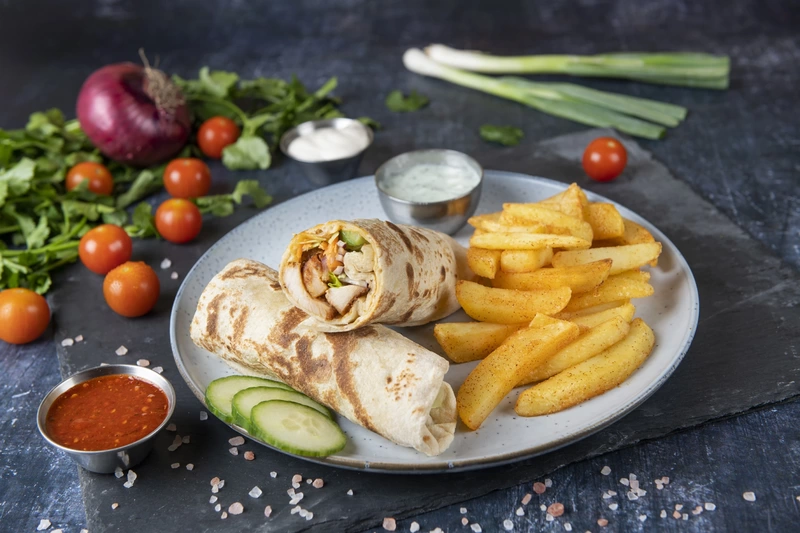 A plate with chicken wraps and chips