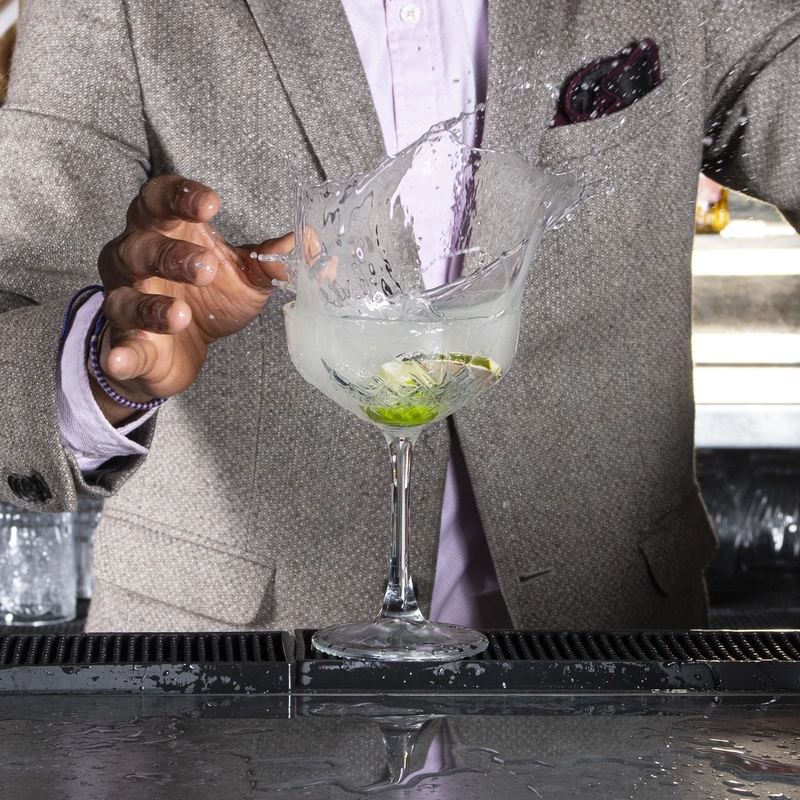 barman making margherita cocktail and spalsing icecubes into the glass
