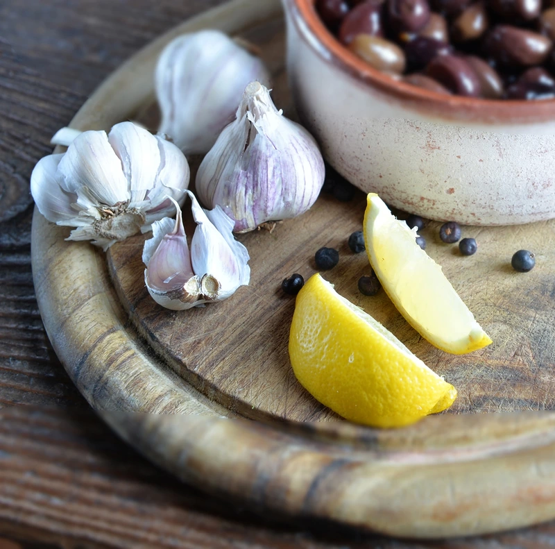 Study of garlic and lemon and olives on a board