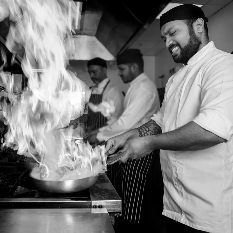 Chef cooking with big flames in frying pan