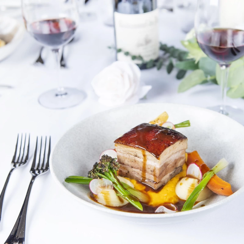 Pork belly and vegetables in fine dining table setting