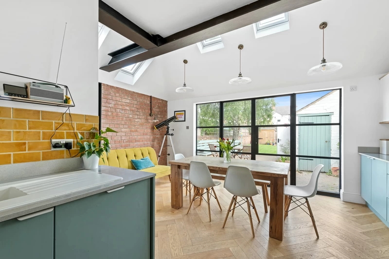 Wide photograph of kitchen dining room with big modern windows