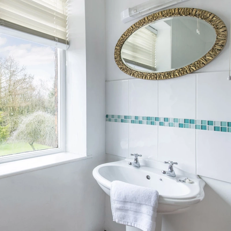 Bathroom sink with mirrow above and view to garden through window